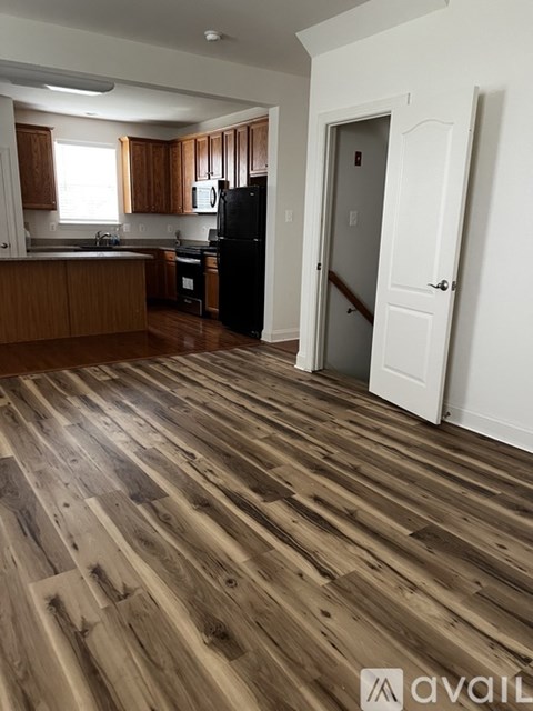 A kitchen with wooden floors and a black refrigerator.