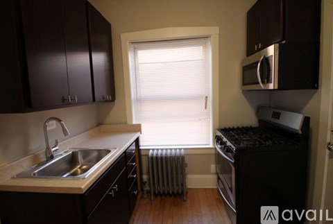 A kitchen with dark brown cabinets and a stainless steel sink.