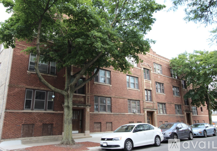 A white car is parked in front of a brick building.
