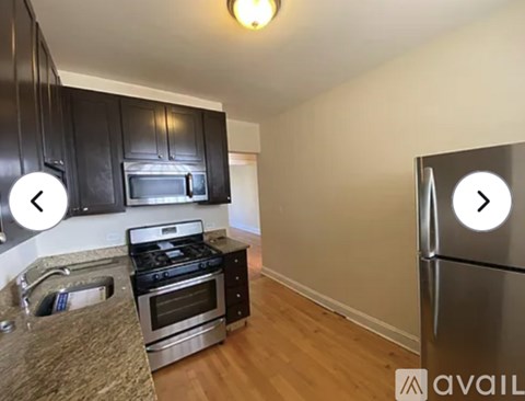 A kitchen with black cabinets and a stainless steel refrigerator.