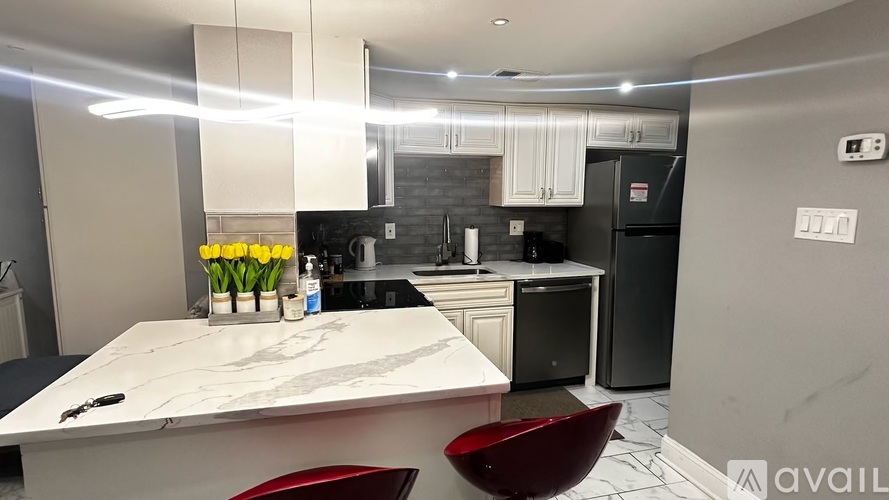 A modern kitchen with a marble countertop and a red chair.