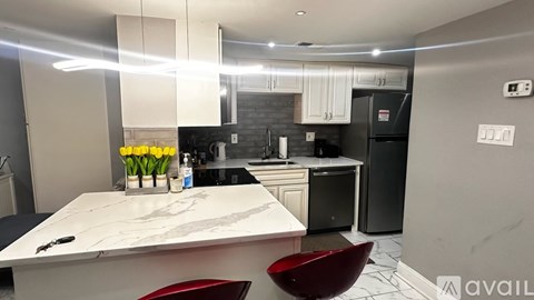 A modern kitchen with a marble countertop and a red chair.