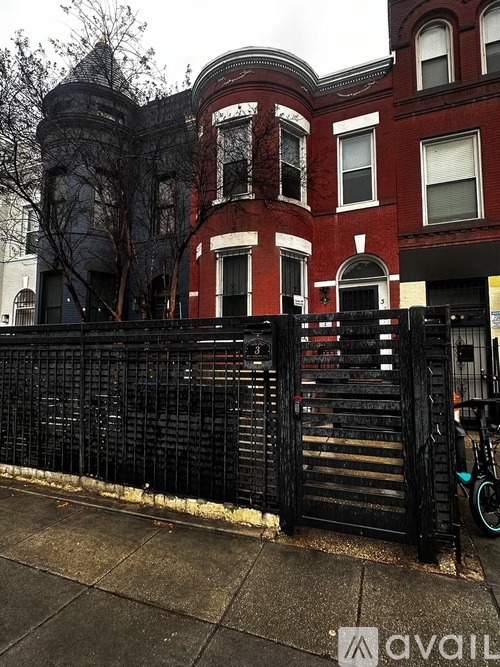 A black iron fence in front of a red brick building.