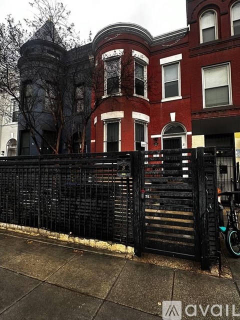 A black iron fence in front of a red brick building.