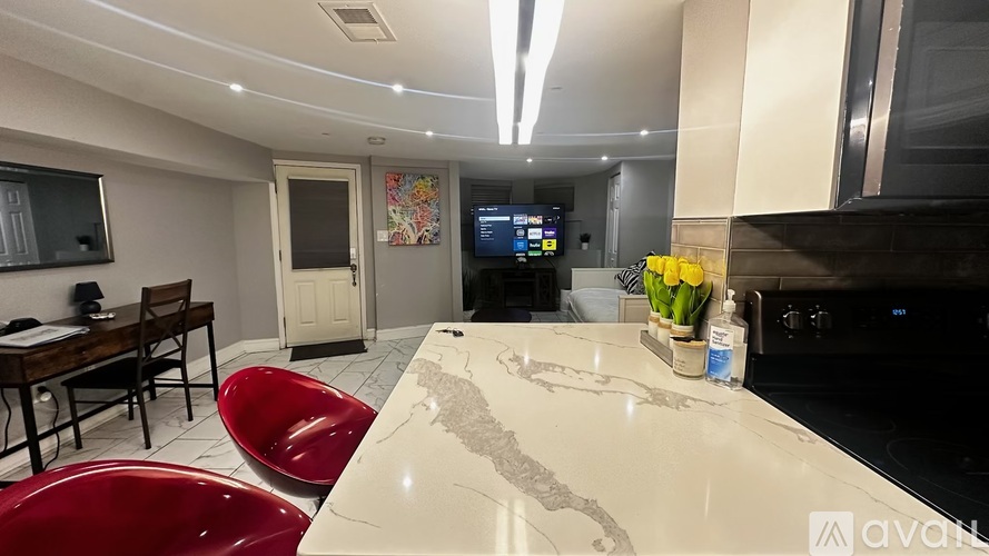 A kitchen with a white countertop and red chairs.