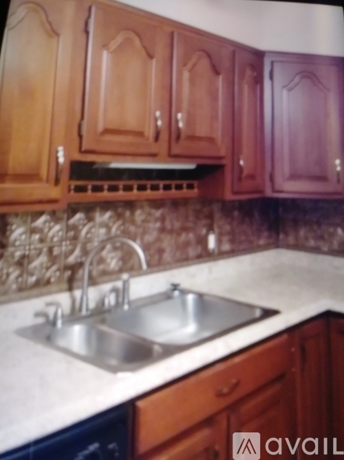 A kitchen with wooden cabinets and a marble backsplash.