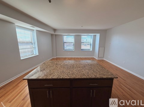 A spacious room with a granite countertop and wooden flooring.