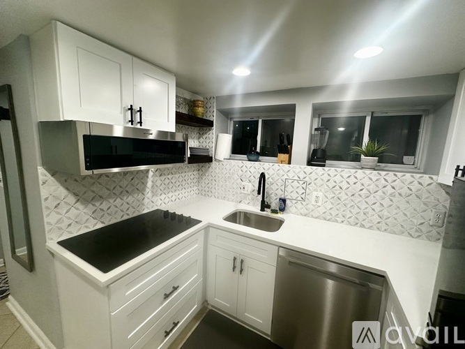 A modern kitchen with white cabinets and a black countertop.