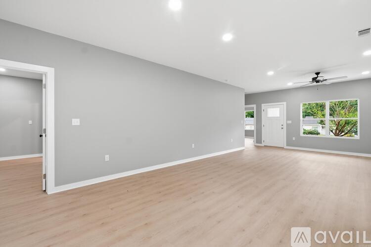 A spacious room with wooden flooring and a ceiling fan.