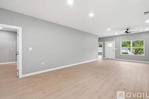 A spacious room with wooden flooring and a ceiling fan.