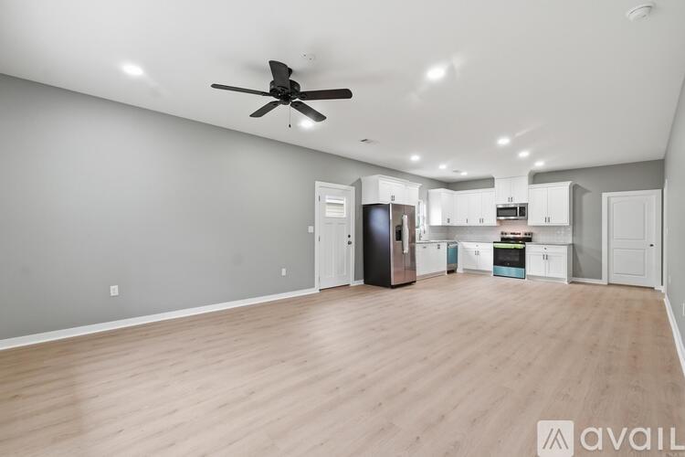 A spacious living room with a ceiling fan and hardwood flooring.