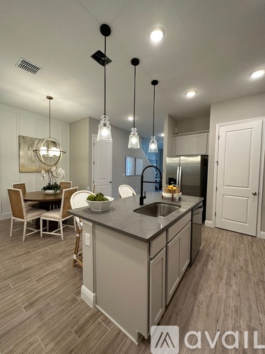 A modern kitchen with a large island and pendant lights.