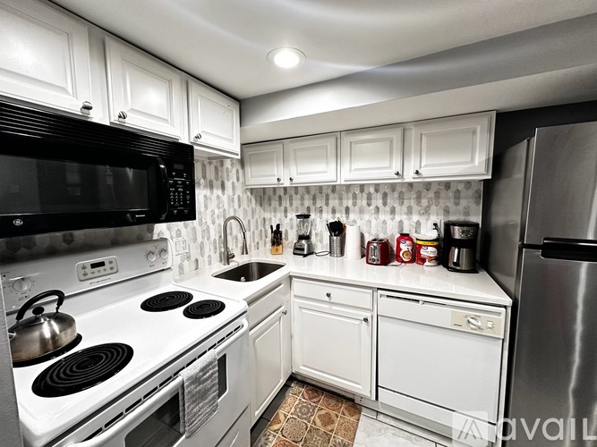 A kitchen with white cabinets and a black microwave.
