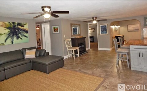 A living room with a black leather couch and a ceiling fan.