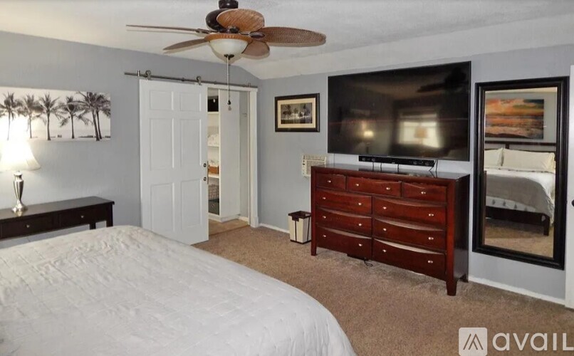 A bedroom with a bed, dresser, and television.