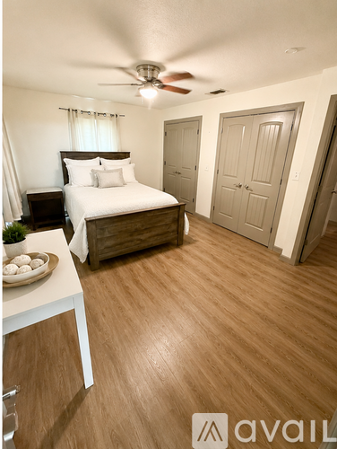 A bedroom with a bed, a ceiling fan, and a wooden floor.