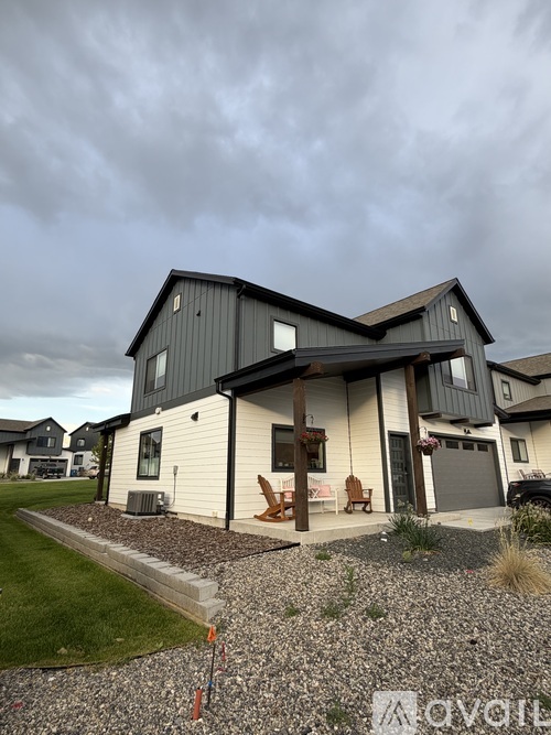 A modern house with a grey roof and a gravel driveway.