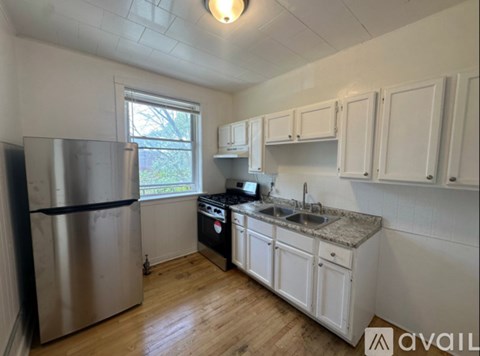 A kitchen with a stainless steel refrigerator and white cabinets.