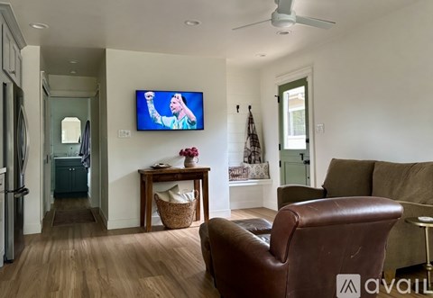 A living room with a brown leather chair and a flat screen TV mounted on the wall.