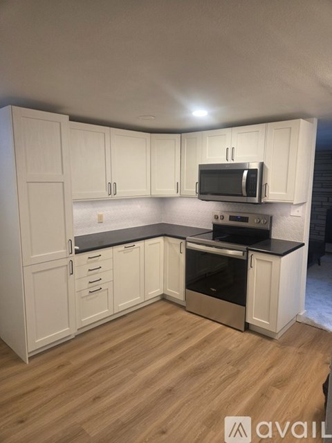 A kitchen with white cabinets and a black countertop.