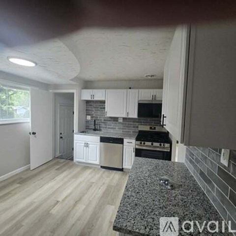 A kitchen with white cabinets and a granite countertop.