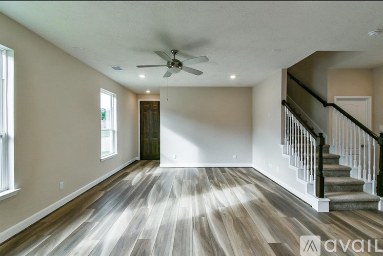 A spacious room with wooden floors and a staircase.