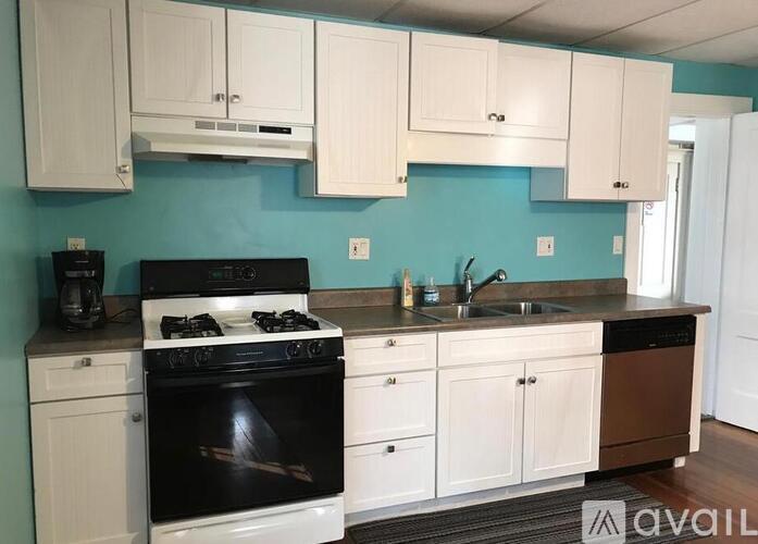 A kitchen with a black stove top oven and white cabinets.