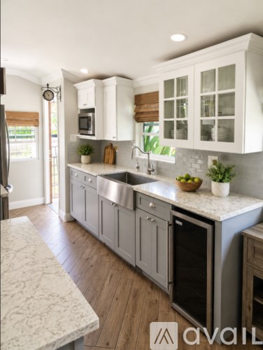 A kitchen with white cabinets and a marble countertop.