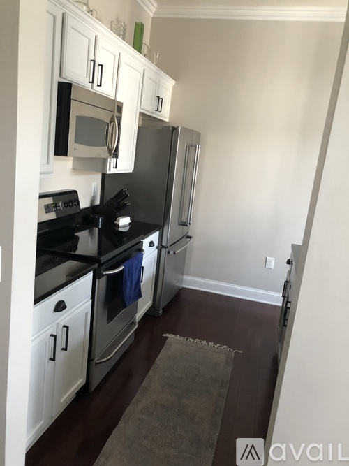 A kitchen with white cabinets and black appliances.
