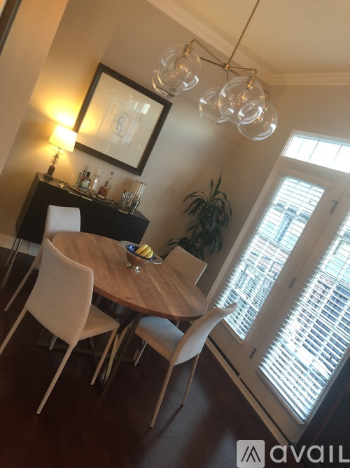 A dining room with a wooden table and white chairs.