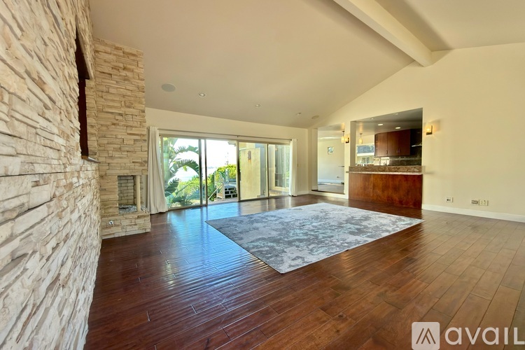A spacious room with wooden floors and a stone wall.