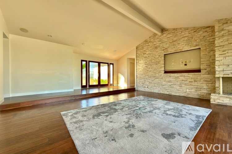 A spacious living room with a stone wall and a rug on the floor.