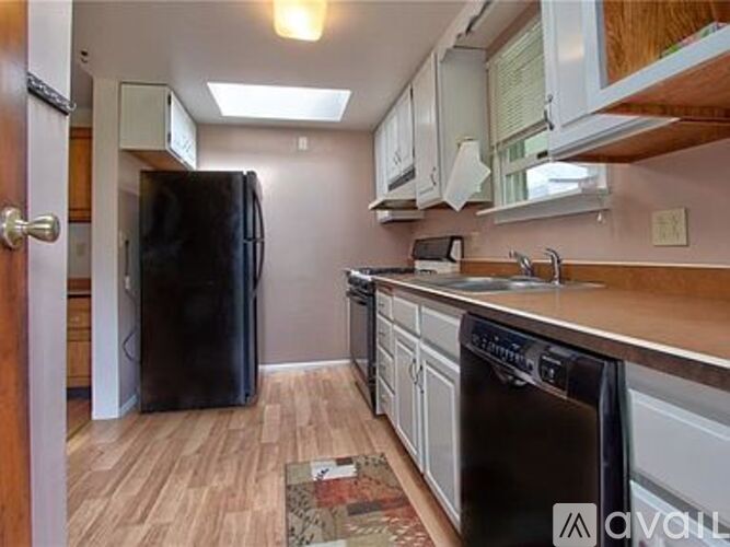 A kitchen with a black refrigerator and stove top oven.