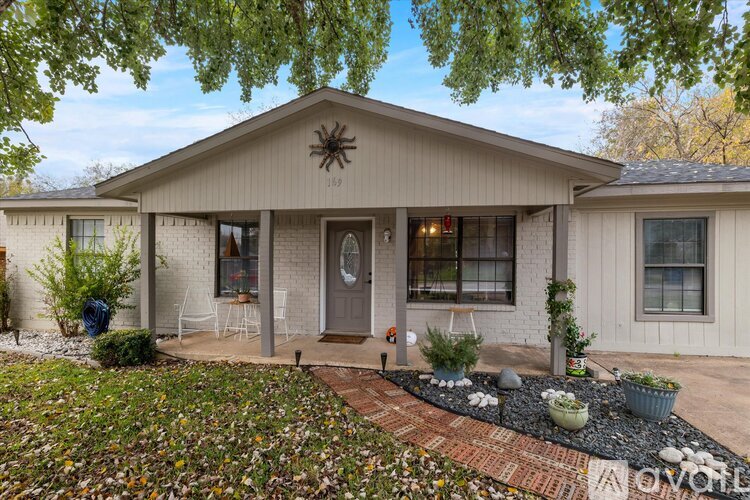 A house with a front yard and a spider decoration on the roof.