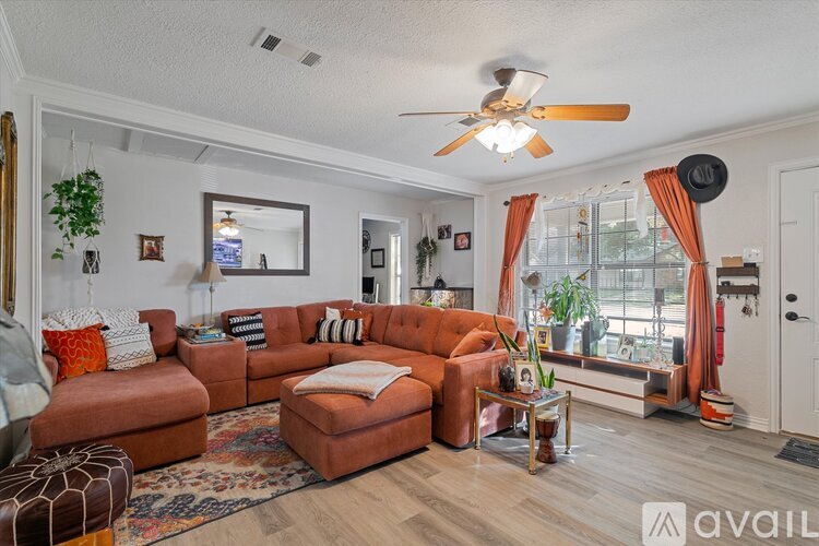A living room with a brown sofa and a ceiling fan.