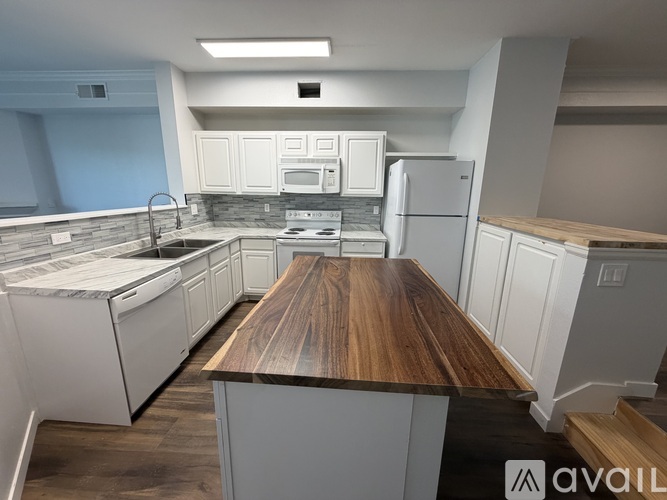 A modern kitchen with white cabinets and a wooden island.