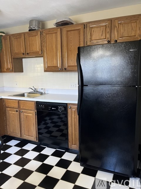 A black fridge in a kitchen with wooden cabinets.