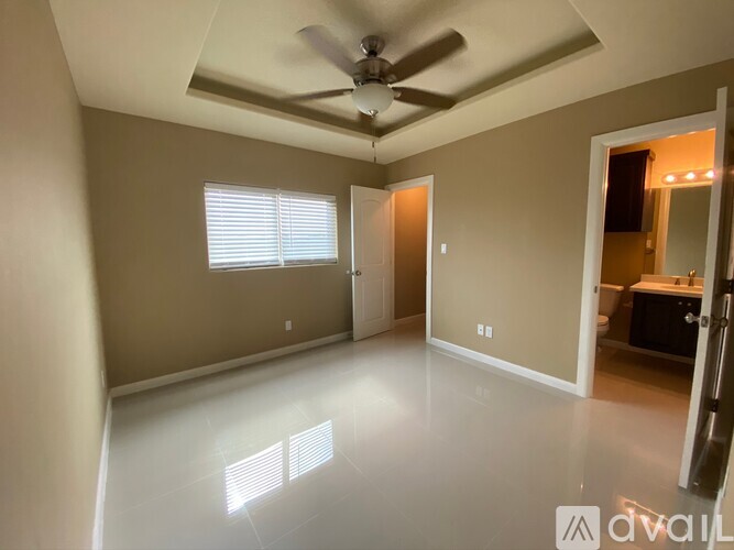 A spacious room with a ceiling fan and a door leading to another room.