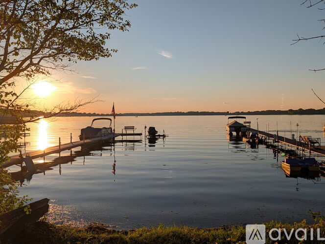 A serene lake with boats docked at the pier during sunset.