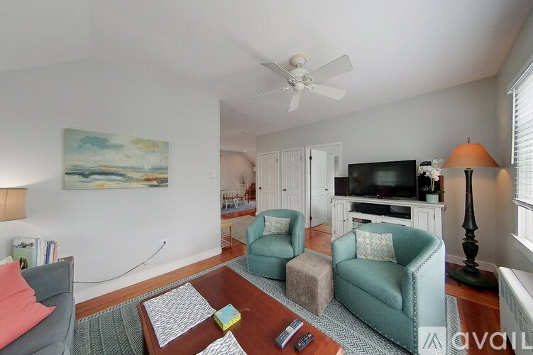 A living room with a grey couch, a green armchair, a coffee table, a television, and a painting on the wall.