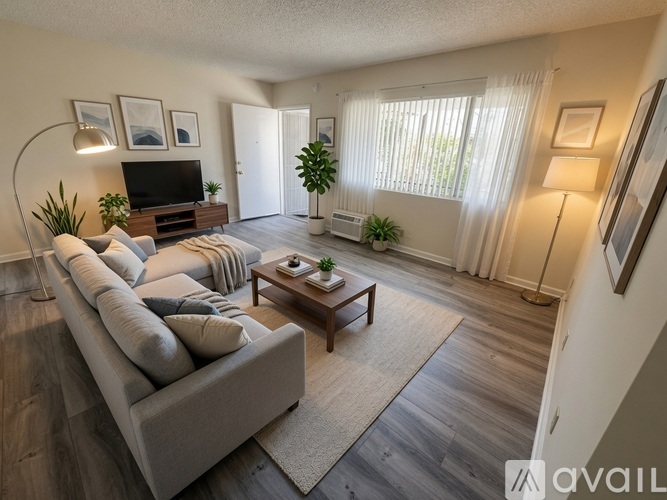 A living room with a grey couch, a wooden coffee table, and a television on a wooden stand.