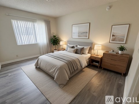 A well-lit bedroom with a large bed, nightstand, and a plant.