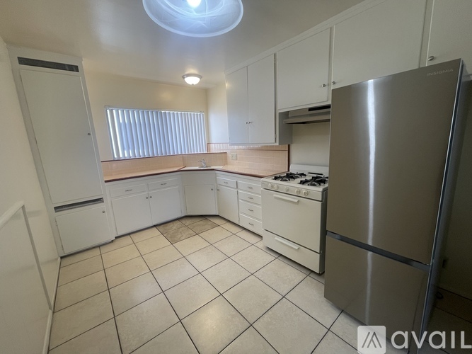 A kitchen with white cabinets and a stainless steel refrigerator.