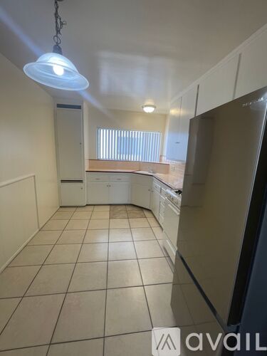 A kitchen with white appliances and tiled flooring.