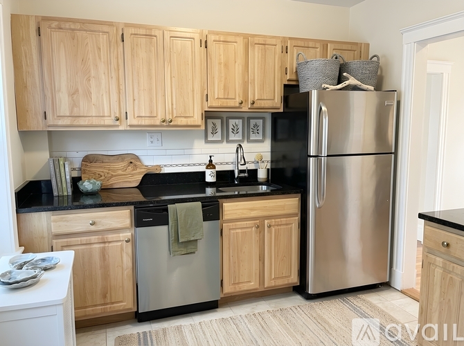 A kitchen with wooden cabinets and a stainless steel refrigerator.