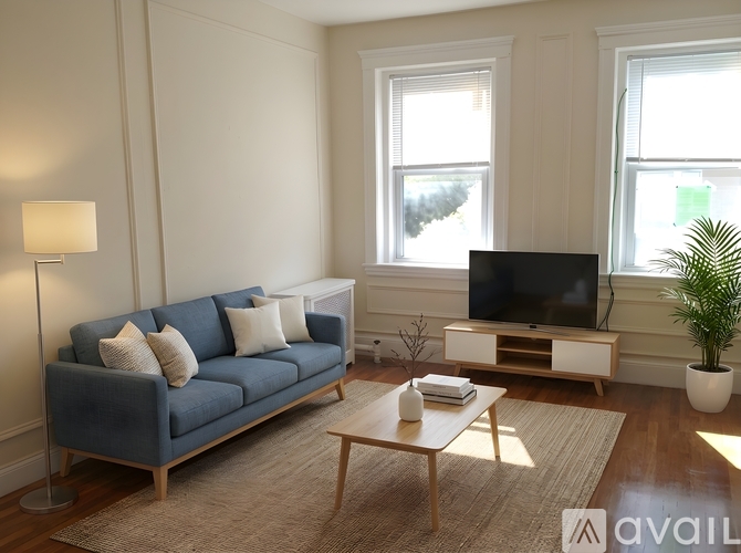 A living room with a blue couch, a wooden coffee table, and a television.