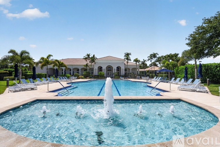 A large pool with a fountain in the middle and a building in the background.