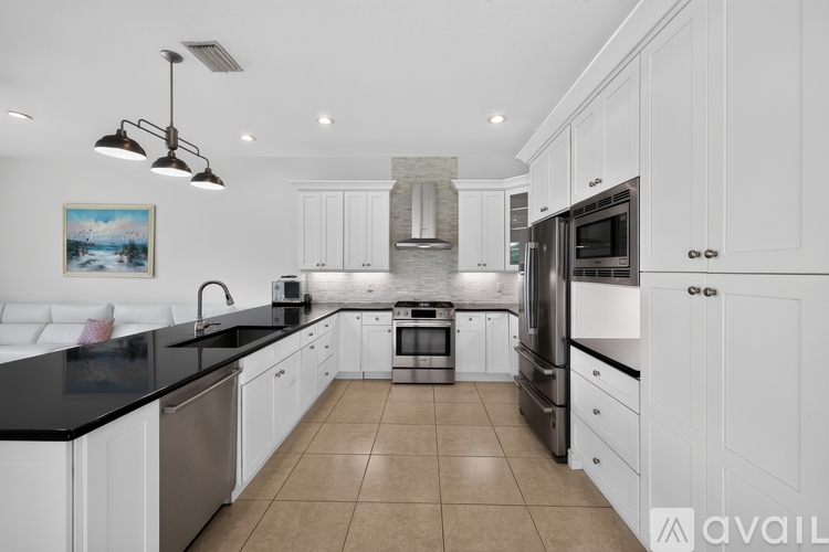 A modern kitchen with white cabinets and black countertops.