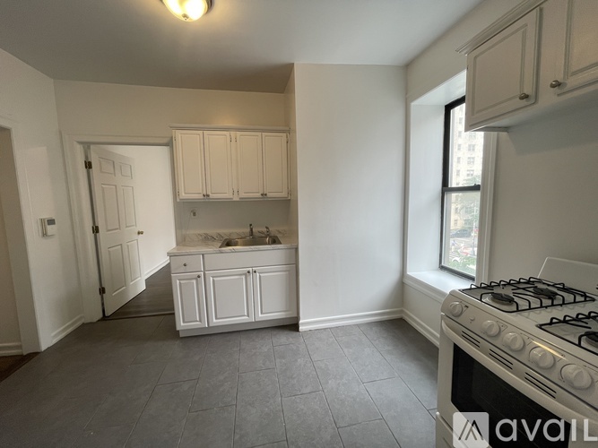 A kitchen with a stove, sink, and cabinets.