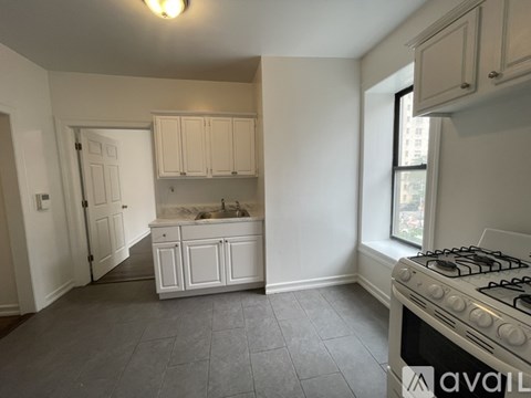 A kitchen with a stove, sink, and cabinets.
